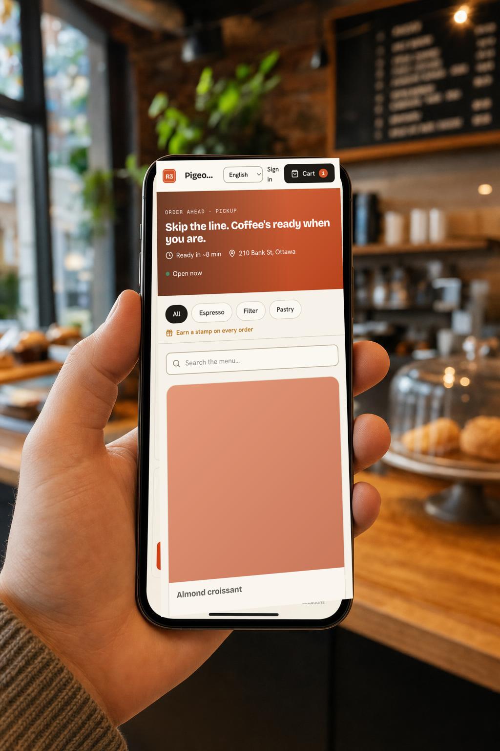 A phone on a café counter showing the R3·POS order-ahead app, with a coffee order ready to pay.